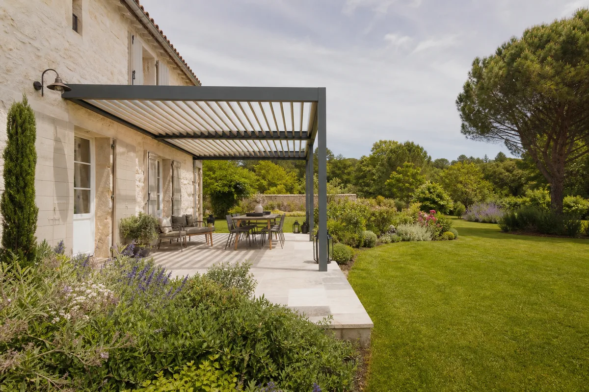 Pergola bioclimatique adossée ouverte sur une pelouse et des massifs