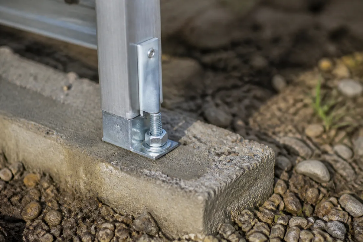 Détail d’un ancrage de serre : profil aluminium fixé sur une base béton par tiges scellées